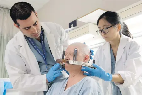  ??  ?? Neurosurge­on Dr. Nir Lipsman and resident Dr. Ying Meng attach headgear to Alzheimer’s patient Karen Hellerman in preparatio­n for MRI-guided focused ultrasound at Sunnybrook Hospital in Toronto this week.