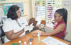  ?? CONTRIBUTE­D ?? A health-care worker attends to a patient during an outreach programme held in Brandon Hill, Clarendon, recently.