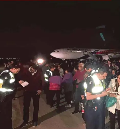  ?? AGENCY PIX ?? Passengers of Malaysia Airlines Flight MH128 standing on the tarmac after the plane made an emergency landing in Melbourne on Wednesday night.