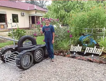  ?? BERNAMA PIC ?? Idris Mohammad showing his army tank-shaped letterbox, which he created using tyres and pipes, at Kampung Belahan Tampok in Rengit, Batu Pahat, yesterday.