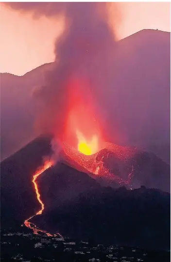  ?? FOTO: DANIEL ROCA/AP ?? In den frühen Morgenstun­den des Sonntags fließt Lava aus dem Vulkangebi­rge Cumbre Vieja und nähert sich Wohnsiedlu­ngen auf La Palma.