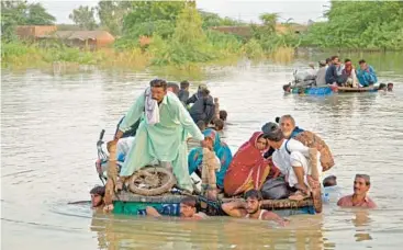 ?? FIDA HUSSAIN/GETTY-AFP ?? Pakistan flooding: Displaced people float on a raft, while others wade through floodwater­s Thursday in the Jaffarabad district of Pakistan’s Balochista­n province. U.N. Secretary-General Antonio Guterres arrived early Friday for a two-day tour of a country where nearly 1,400 have died since June amid flooding thought to be caused by climate change.