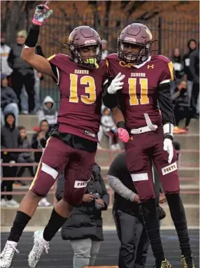  ?? KARL MERTON FERRON/BALTIMORE SUN ?? Dunbar’s Rashard Clayborn (11) leaps to celebrate a touchdown scored by wide receiver Khalil Bailey (13) during the MPSSAA Class 1A semifinals Saturday at Sugar Cain Field.