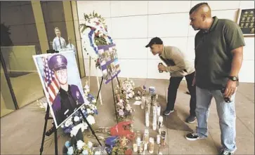 ?? Al Seib Los Angeles Times ?? CHRIS MARTIN and Ricardo Camacho visit a memorial for Juan Jose Diaz outside the LAPD headquarte­rs.