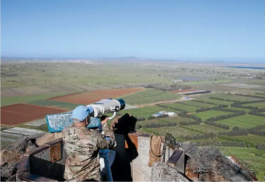  ?? PHOTO: GETTY IMAGES ?? A UN observer looks through binoculars towards the Syrian city of Quneitra from Mt Bental on the Israeli side of the border. The city of Quneitra is located on the buffer zone between Israel and Syria in the Golan Heights.