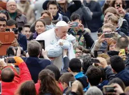  ?? — AP ?? Pope Francis kisses a baby as he is driven through the crowd during his weekly general audience in St. Peter’s Square, at the Vatican, on Wednesday.