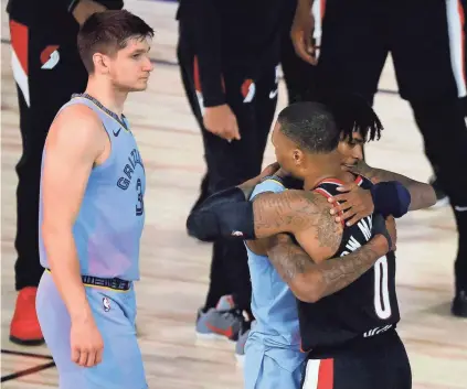  ?? KEVIN C. COX/POOL PHOTO VIA AP ?? The Trail Blazers’ Damian Lillard, right, hugs the Grizzlies’ Ja Morant after Saturday’s Western Confrence play-in game in Lake Buena Vista, Fla.