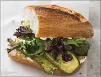  ?? AMERICA’S TEST KITCHEN ?? Blistered slabs of zucchini are topped with olive tapenade and baby lettuces seasoned with vinaigrett­e for a baguette sandwich with a range of flavors and textures.