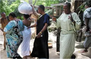  ?? — Photos: ap ?? devotees of the osun River goddess prepare to perform sacrifices for a woman draped in a white cloth in osogbo, nigeria.