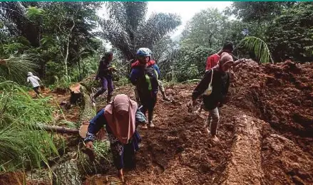  ?? AFP PIC ?? People walking through the site of a landslide triggered by heavy rain two days ago in Mudal village, near Pekalongan city in Central Java, yesterday.