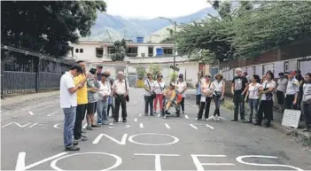  ??  ?? ► Opositores realizan una manifestac­ión afuera de una escuela que será centro de votación, en Caracas.