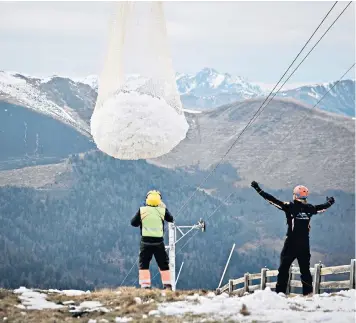  ??  ?? A helicopter dumps a load of snow on a slope in the Superbagne­res ski resort in the French Pyrenees to help create skiing conditions