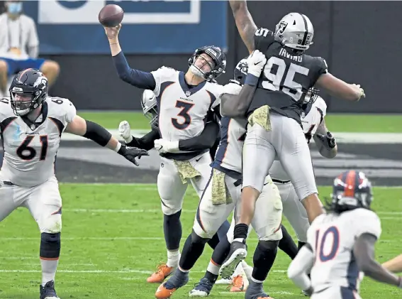  ?? Andy Cross, The Denver Post ?? Broncos quarterbac­k Drew Lock is hit from behind by Raiders defensive end Arden Key while throwing a pass Sunday at Allegiant Stadium.