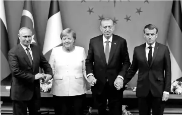  ?? — Reuters photo ?? (From left) Putin, Merkel, Erdogan and Macron hold hands at a news conference after a Syria summit, in Istanbul.
