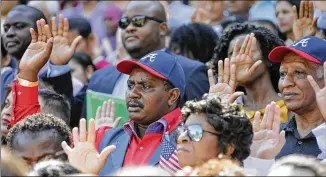  ?? BOB ANDRES /AJC FILE ?? New citizens take their oath of allegiance during a naturaliza­tion ceremony at Turner Field. Out of all U.S. metro areas, Atlanta holds the fourth-largest Black immigrant population.