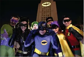  ?? AP PHOTO BY CHRIS PIZZELLO ?? Fans dressed as characters from “Batman” pose in front of a Bat-signal projected onto City Hall following a tribute to “Batman” star Adam West on Thursday in Los Angeles.