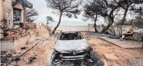 ?? FOTO: DPA ?? Komplett zerstört: Eine Frau sitzt in Mati nahe Athen vor ihrem ausgebrann­ten Haus und dem Wrack ihres Autos.