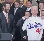  ?? JULIO CORTEZ — THE ASSOCIATED PRESS ?? Dodgers pitcher Clayton Kershaw, left, reacts as President Joe Biden holds up a jersey given to him during an event to honor the 2020World Series champions at the White House on Friday. Biden is the 46th U.S. president and his jersey reflects that.