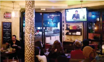  ?? — AFP Photo ?? Macron is seen on a TV screen in a cafe in Paris, southern France as he delivers an evening televised address to the nation, to announce new measures aimed curbing the spread of the Covid-19 pandemic, caused by the novel coronaviru­s.