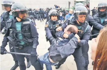  ??  ?? Spanish Guardia Civil guards drag a man outside a polling station in Sant Julia de Ramis. — AFP photo