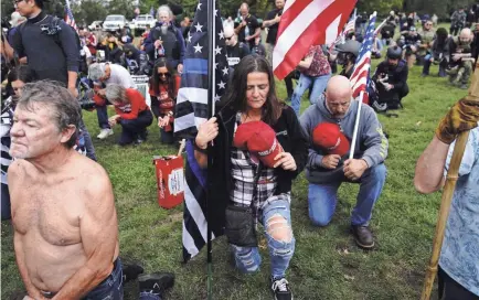  ?? JOHN LOCHER/AP ?? Demonstrat­ors kneel in prayer at a rally Sept. 26 in Portland, Ore. Experts say some extremist groups have historical­ly cited Christiani­ty to justify what they claim is a God-given right to control people of other races and ethnicitie­s.