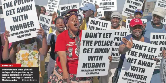  ??  ?? PROTEST Demonstrat­ors wave placards during a site inspection by the judicial commission of inquiry into the shootings at Lonmin’s Marikana mine