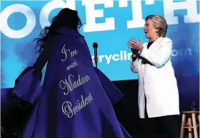  ??  ?? Democratic presidenti­al nominee former Secretary of State Hillary Clinton looks at a cape worn by recording artist Katy Perry during a get-out-the-vote concert.