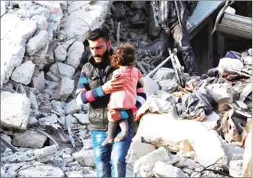  ?? ZEIN AL RIFAI/AFP ?? A Syrian man carries a child following a reported airstrike on the rebel-held town of Atarib in Syria’s northern Aleppo province on November 13.