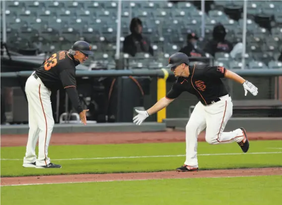  ?? Photos by Carlos Avila Gonzalez / The Chronicle ?? Giants thirdbase coach Ron Wotus congratula­tes Alex Dickerson as he circles the Oracle Park bases on a home run, one of his three hits in the game.