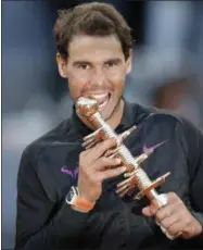  ?? DANIEL OCHOA DE OLZA — THE ASSOCIATED PRESS ?? Spain’s Rafael Nadal bites the trophy as poses for photograph­ers after winning the final of the Madrid Open tennis tournament in two sets, 7-6 (10-8), 6-4, against Austria’s Dominic Thiem in Madrid, Spain, Sunday.