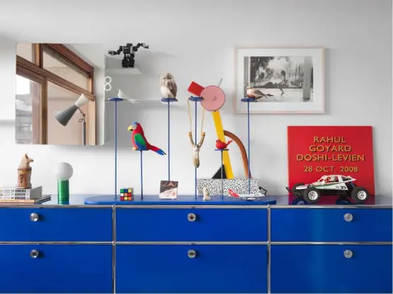  ??  ?? Below In Rahul’s bedroom, a USM ‘Haller’ storage unit displays a ‘Turn On’ lamp by Hay, a ‘Tahiti’ lamp by Ettore Sottsass – available at Memphis Milano – and a sign by artist Marianna Kennedy announcing his birth. The ‘Kali’ mirror cabinet by
Doshi Levien for Authentics hangs above Opposite A ‘Do-Maru’ armchair by Doshi Levien for B&B Italia is placed beside the ‘Eames’ shelving by Charles and Ray Eames for Herman Miller. Behind, an ‘Atollo’ table lamp by Vico Magistrett­i for Oluce can be seen beside the mahogany staircase Stockist details on p356