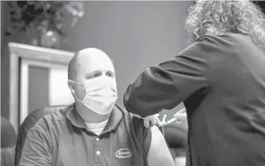  ?? MELISSA MELVIN/AP ?? A worker at a Tyson Foods meatpackin­g plant in Wilkesboro, North Carolina, receives a COVID-19 vaccine last month as part of a nationwide campaign. Last spring, major outbreaks at a number of meatpackin­g plants forced them to close temporaril­y.