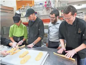  ?? MICHAEL SEARS / MILWAUKEE JOURNAL SENTINEL ?? Dina Menzl-Russo (left) helps Mark Wilets twist bread as Rabbi Levi Stein watches and Jonathan Frank rolls out dough at Friendship Bakery. They were making challah bread.