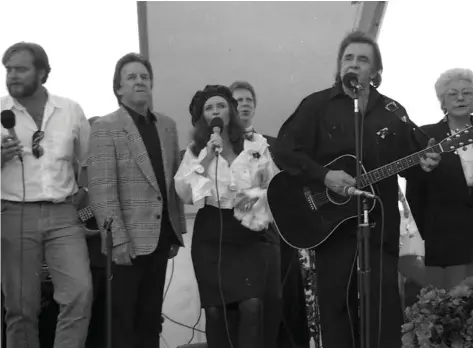  ?? (Special to The Commercial) ?? During the March 31, 1994, dedication concert for the Kingsland Post Office, Cash family members joined in singing the Carter family classic, “Shall the Circle Be Unbroken.” They are son John Carter Cash (from left), brother Tommy Cash, June Carter Cash, Reggie Lisemby, Johnny Cash and his sister Louise.