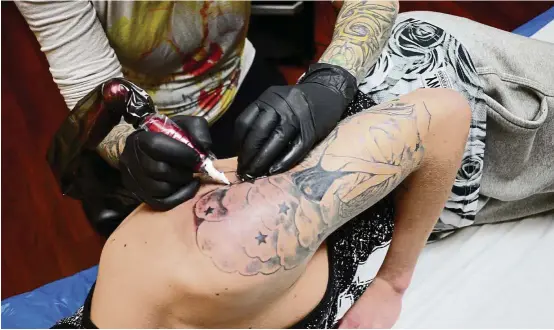  ??  ?? Dubosque ( left) tattoos the arm of teenager Timothee at her Atelier Paradise Tattoo in Paris. — AFP