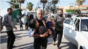  ?? / AP ?? A PALESTINIA­N man carries a wounded boy following an Israeli bombardmen­t in the Maghazi refugee camp, central Gaza Strip, Tuesday, April 16, 2024. Several people were killed in a strike in Maghazi camp in Central Gaza on Tuesday.