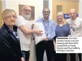  ??  ?? Generous Arun Iyer (centre) hands over the hearing aids from NHS Lanarkshir­e to Frank Devine and Paul Lafferty of Project Gambia