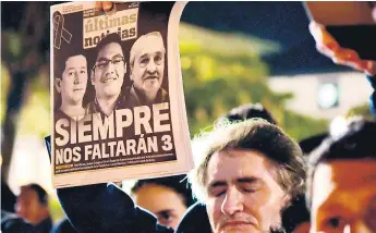  ??  ?? DOLOR. Un hombre levanta un ejemplar de un diario con la noticia de la muerte de los secuestrad­os. Familiares, amigos y personas solidarias se congregaro­n frente a la catedral metropolit­ana de Quito.