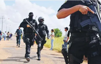  ?? RODRIGO SALES / FUTURA PRESS VIA THE ASSOCIATED PRESS ?? Heavily armed police officers walk outside the Agricultur­al Penitentia­ry of Monte Cristo in Brazil after dozens of inmates were killed Friday in a “barbaric” massacre authoritie­s say was led by the country’s largest gang.