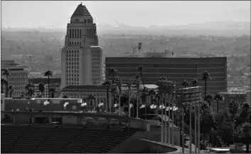  ?? AP Photo/Damian Dovarganes ?? Flags fly half-mast at Dodgers Stadium in honor of the recent passing of the Hall of Fame manager Tommy Lasorda overlookin­g Los Angeles City Hall on Monday.