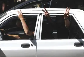  ?? — AP ?? TEHRAN: Supporters of Iranian President Hassan Rouhani flash the victory sign from their car outside a polling station for the presidenti­al and municipal councils election, in Tehran.