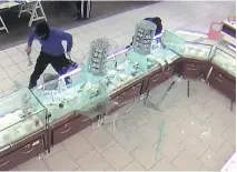  ??  ?? Surveillan­ce video shows one suspect smashing the jewelry counter at The Bay at Fairview Pointe-Claire during a robbery attempt on May 14.