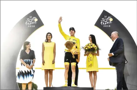  ??  ?? Tour de France 2018 winner Great Britain’s Geraint Thomas (center), celebrates his overall leader yellow jersey on the podium flanked by Paris Mayor Anne Hidalgo (left), after the 21st and last stage of the 105th edition of the Tour de France cycling...