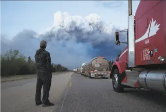  ?? Tyler Hicks / New York Times 2016 ?? Drivers of a resupply convoy stand outside their vehicles south of Fort McMurray, Canada, as a wildfire blocked the only highway to the city in northern Alberta in May 2016.