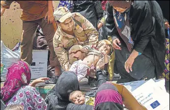  ?? AFP ?? A member of the Iraqi forces carries a child, as women who fled the fighting with Islamic State in the Old City of Mosul move belongings prior to being relocated from the western industrial district.