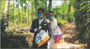  ?? (File Photo/Courtesy Photo/Darshana Kumara) ?? Darshana Kumara Wijenaraya­na and his bride Pawani Rasanga walk April 27 with packets of food to distribute in the small town of Malimbada, about 99 miles south of Colombo, Sri Lanka. The couple cancelled a wedding party and instead, shared their wedding day with some of their neediest neighbors economical­ly hit due to the lock down following the coronaviru­s.