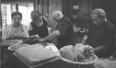  ??  ?? PHOTOS: TYLER ANDERSON / NATIONAL POST Don di Cocco, far right, cuts bread with his guests before a lunch at his home in Sarnia, Ont.