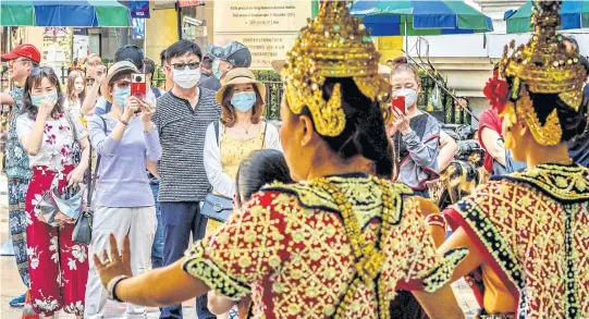  ?? AFP ?? Chinese tourists with face masks watch a traditiona­l Thai dance at Erawan Shrine, a popular spiritual landmark in Bangkok.