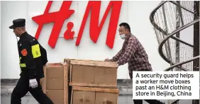  ??  ?? A security guard helps a worker move boxes past an H&M clothing store in Beijing, China