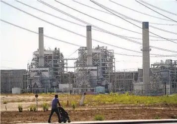  ?? JAE C. HONG AP FILE ?? A man pushes a stroller near the AES power plant in Redondo Beach last year. The California Energy Commission voted Wednesday to extend the life of three gas power plants in Southern California through 2026.